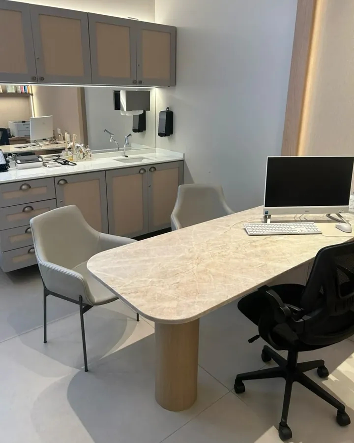 Sala de atendimento da Dra. Larissa Basmage: mesa de mármore claro, cadeiras para o paciente e bancada com pia